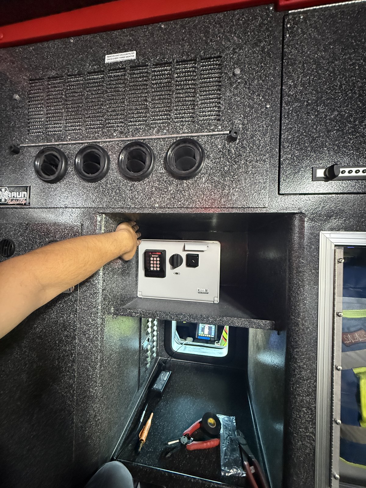 Technician servicing the action-area console and lockbox in a Braun ambulance module